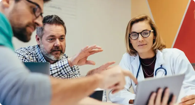 Médica y profesionales analizan un plan de salud en una mesa de trabajo.